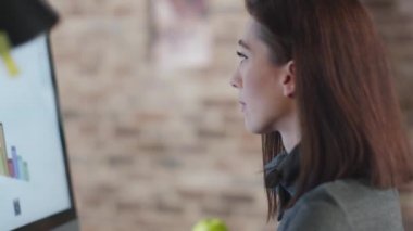 Genç esmer kadın bir çatı katında bir monitör önünde bir grafik üzerinde çalışıyor.