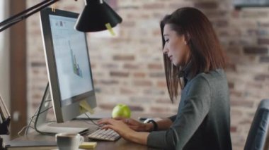 Genç esmer kadın bir çatı katında bir monitör önünde bir grafik üzerinde çalışıyor.