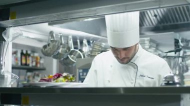 Restoranda ya da otelde ticari bir mutfakta profesyonel bir aşçı yeşil sebzeleri dilimliyor..
