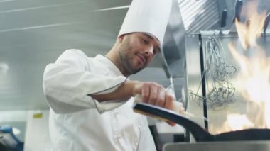 Ticari mutfak profesyonel şef gıda ile bir tava ateşe hazırlanıyor.