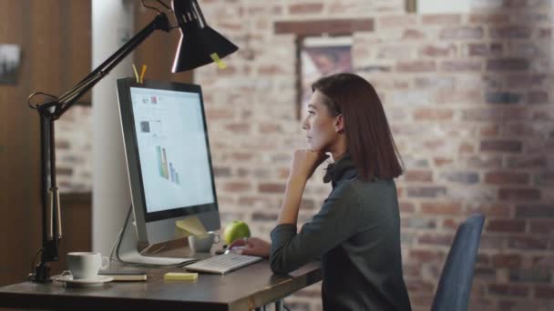 Mladá bruneta žena pracuje s grafy před monitorem v podkroví. — Stock video