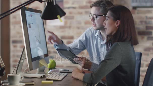 Joven hombre y mujer están trabajando en una computadora mientras discuten un proyecto. — Vídeo de stock