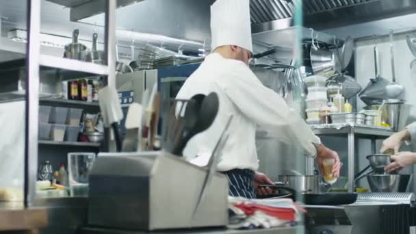 Três chefs profissionais em uma cozinha comercial em um restaurante ou hotel estão preparando comida . — Vídeo de Stock