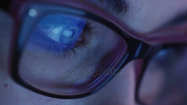 Primer plano de ojo de mujer en gafas mirando una pantalla de tableta en la oscuridad . — Vídeos de Stock