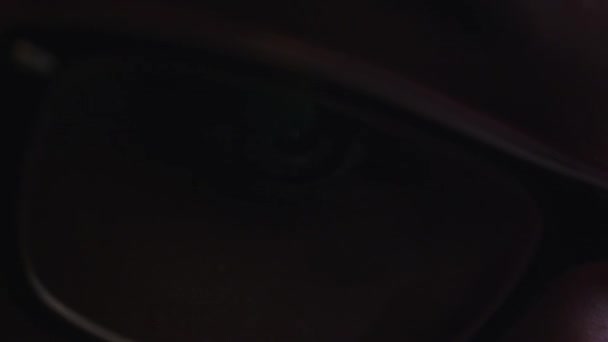 Close-up shot van vrouw oog in glazen staren naar een computerscherm werken in het donker. — Stockvideo