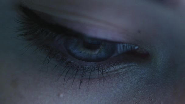 Gros plan de l "œil d'une femme qui regarde un écran de tablette dans le noir .