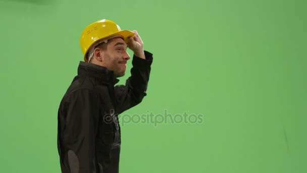 ハード帽子の建設労働者は、モックアップを歩いている背景に緑色の画面. — ストック動画