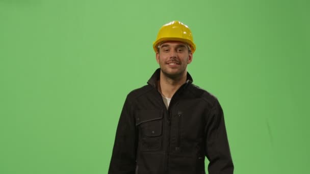 Il lavoratore edile con un cappello rigido cammina su uno schermo verde modellato sullo sfondo . — Video Stock