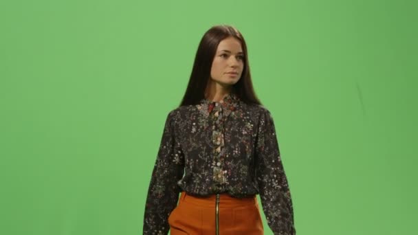 Mulher morena casual está andando em uma tela verde de mock-up no fundo . — Vídeo de Stock