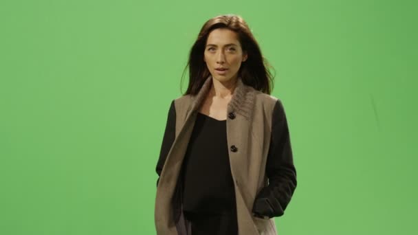 Casual brunette vrouw loopt op een mock-up groen scherm op de achtergrond. — Stockvideo