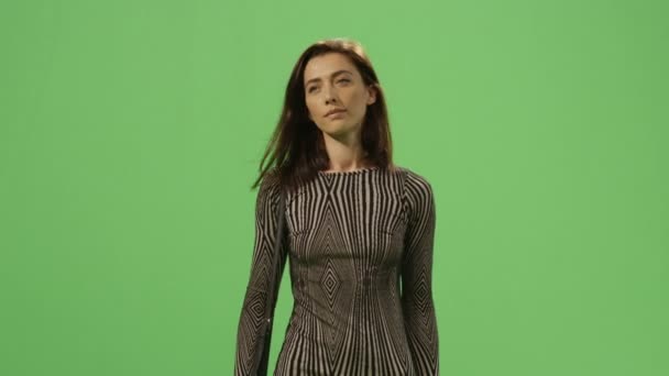Брюнетка в платье идет на макете зеленый экран на заднем плане . — стоковое видео