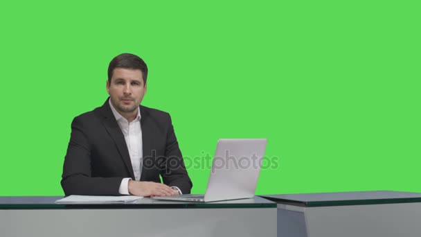 Ραδιοτηλεοπτικός φορέας πολυμέσων κάθεται σε ένα τραπέζι και να μιλάμε για μια μακέτα πράσινη οθόνη στο παρασκήνιο. — Αρχείο Βίντεο