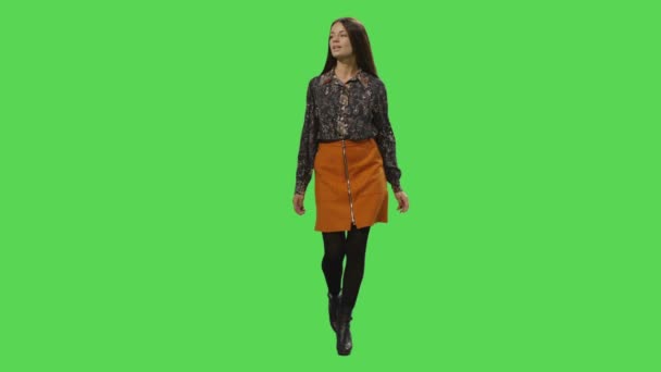 カジュアルな若いブルネットの少女はモックアップを歩いて緑背景の画面. — ストック動画