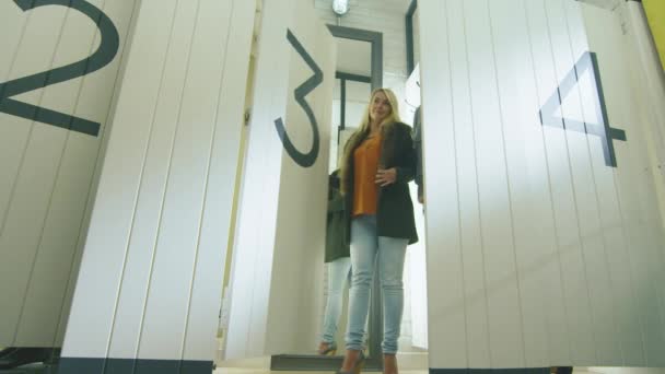 Jong blond meisje uitproberen herfst kleding in een paskamer van een warenhuis. — Stockvideo