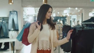 Mutlu genç esmer kız yine de bir giyim mağazası yürüyor.