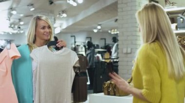 İki sarışın kızlar arasında bir beyaz ve bir mağaza içinde duran pembe bir elbise tercih ediyor.