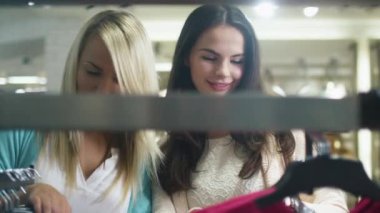 İki neşeli genç kız elbiseleri bir mağaza alışveriş.