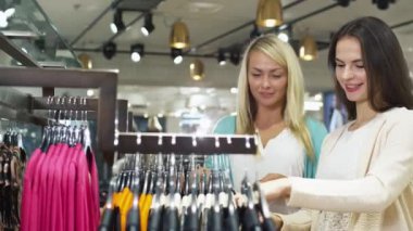 İki mutlu genç kız elbiseleri bir mağaza alışveriş.