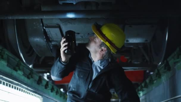 Technician in Hard Hat with Flashlight in Hand Inspecting Train — Stock Video