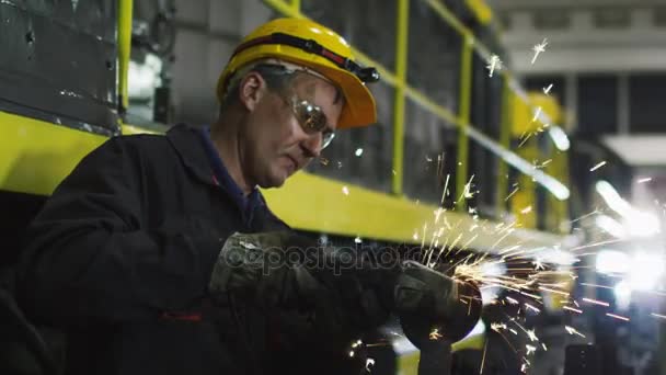 Trabajador con amoladora angular hace metalurgia en ambiente industrial. Reflejos de chispa — Vídeo de stock