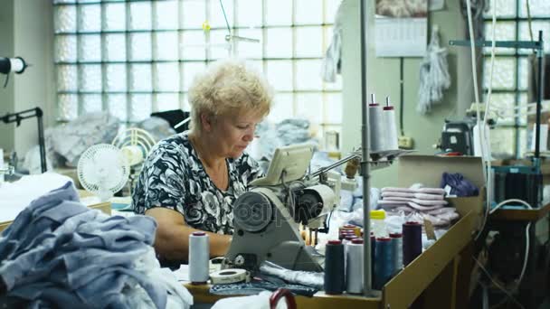 Senior garment worker sta lavorando su una macchina da cucire in un'officina . — Video Stock