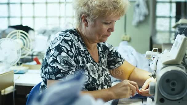 Costurera senior está trabajando en una máquina de coser en una fábrica de ropa . — Vídeo de stock