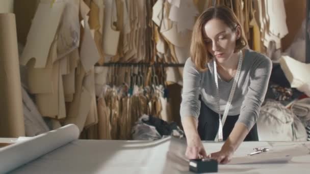 Σχεδιαστής ρούχα λειτουργεί με μετρήσεις σε ένα πίνακα στούντιο. — Αρχείο Βίντεο