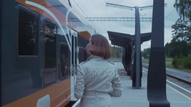 Kendine güvenen kadın trende yürüyüş siperde kapıları tren istasyonu ve içine almak.