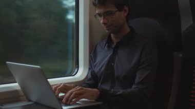 Trende yolculuk sırasında dizüstü bilgisayarda çalışan adam