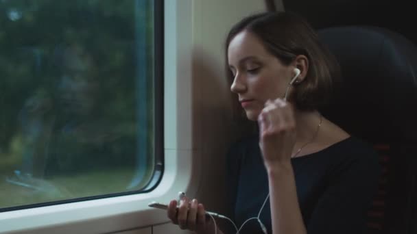 女の子は電車で旅行中、音楽を聴いてください。 — ストック動画