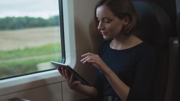 Женщина с планшетного компьютера рядом с окном в движущемся поезде — стоковое видео