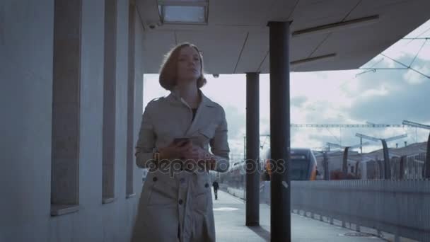 Fiduciosa donna in trincea a piedi nella stazione ferroviaria — Video Stock