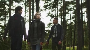 İki Genç çiftler yaprakları frenleme güneş ışığı ile güzel bir sonbahar ormanda yürüyor.