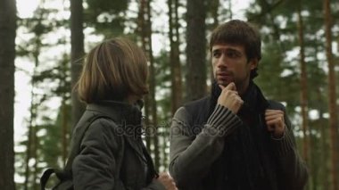 Uzun saçlı erkek ve karanlık sonbahar giysileri esmer kadın bir ormanda ayakta ve etrafa.