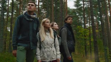 Bir grup insan sonbahar giysileri bir ormanda ayakta ve etrafa vardır.