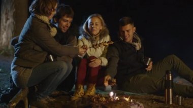 Bir grup insan gece kamp ateşinin üzerinde et hazırlıyoruz.