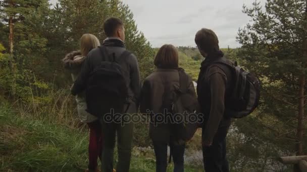 Groep van mannen en vrouwen een herfst boslandschap bekijkt met een vijver vanaf een heuvel. — Stockvideo
