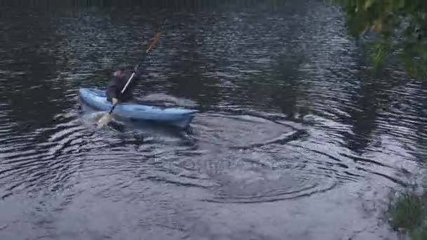 L'uomo sta girando il kayak con una pagaia in un fiume e galleggia via . — Video Stock