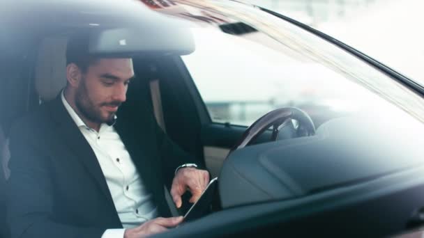 ビジネスマン幹部の黒い車の中に座っている間タブレットを使用して. — ストック動画