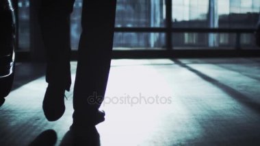 İş takım elbiseli adamı güneş ışığı yansıtan binaları görünüyor büyük bir pencere doğru yürüyor.