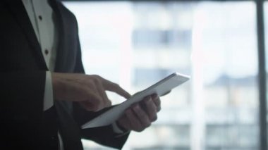 Bir işadamı bir tablet kullanarak büyük bir pencere yanında takım elbiseli Close-Up.