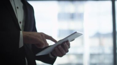 İş takım elbiseli adamı bir garajda bir çift araba ve büyük bir pencere yanında tablet kullanma.