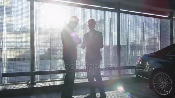 Twee zakenman een gesprek en een akkoord met een handdruk bij een garage-parkeerplaats. — Stockvideo