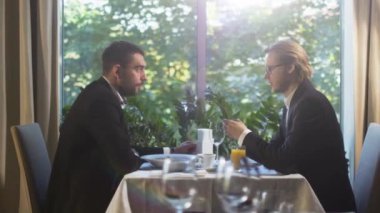 Takım elbiseli iki işadamı var bir konuşma bir restoranda öğle yemeği saatinde.