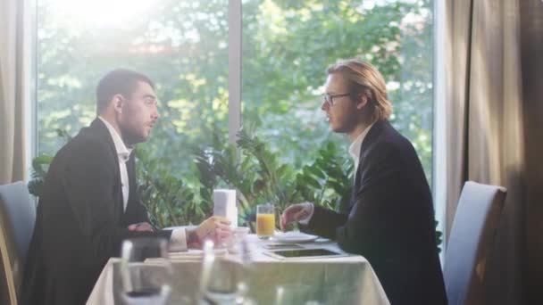 Deux hommes d'affaires en costume ont une conversation et parviennent à un accord avec une poignée de main dans un restaurant . — Video