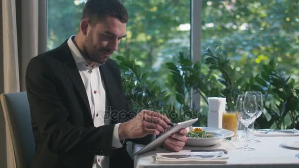 Επιχειρηματίας εργάζεται σε ένα tablet με μια γραφίδα σε ένα εστιατόριο. — Αρχείο Βίντεο