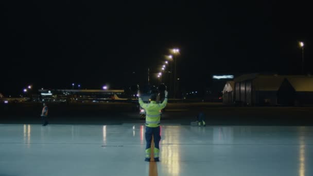 Repülőgép koordinátor jeleket egy repülőgép hangár felé való elmozdulás az éjszakában. — Stock videók