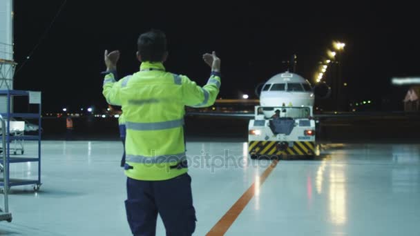 Flygplan marskalk styr ett flygplan i natten för att gå mot hangaren. — Stockvideo