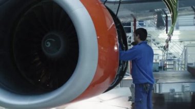 Uçak motoru bir hangarda uçak bakım mekanik bir flaş ışığı ile inceler.