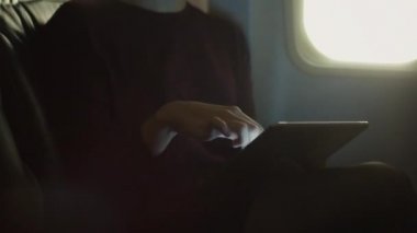 Yakın çekim genç kadın bir pencere yanında tablet içinde bir uçak kullanma.